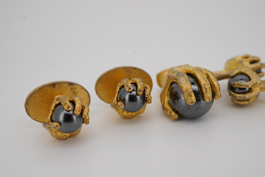 A modern gilt sterling and hematite set six piece dress stud set, modelled as a hand grasping a sphere, comprising a pair of cuff links 30mm and four studs. Condition - poor to fair